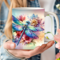Custom name dragonfly flower mug. Vivid color sublimated mug design. Close-up of dragonfly mug being held by a woman, in her garden.